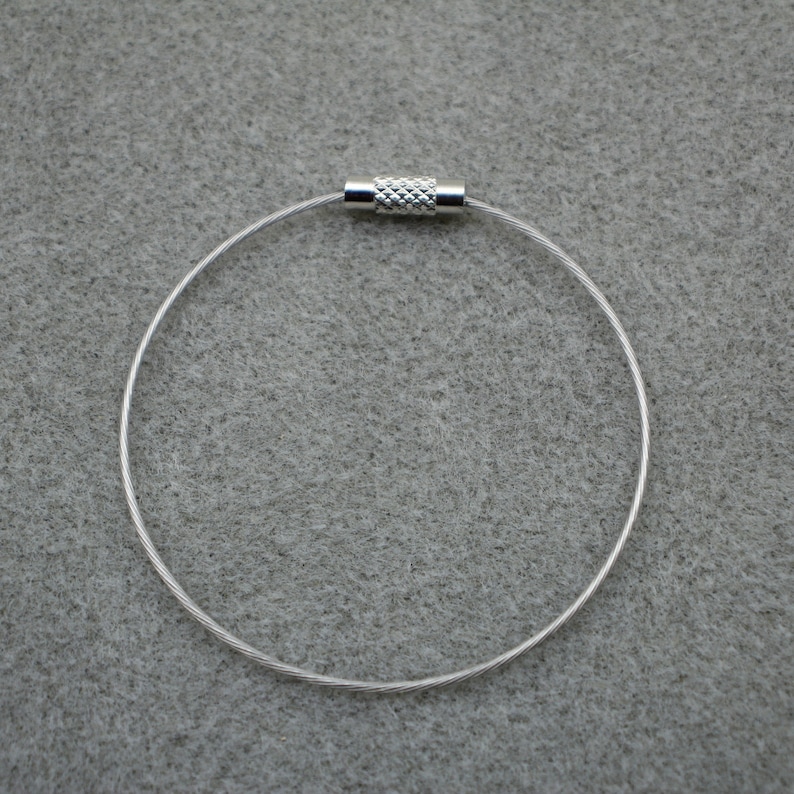 Puede incluir: Un llavero de plata con un dise&ntilde;o de cable trenzado y un cierre de plata.
