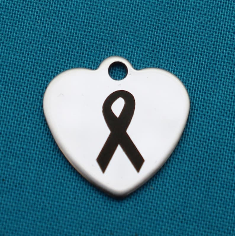 May include: A silver heart-shaped charm with a black ribbon engraved on it.
