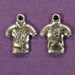 May include: Two silver charm pendants shaped like football jerseys. One jersey has the word "Soccer" and a football on the front. The other jersey has the number "9" on the back.
