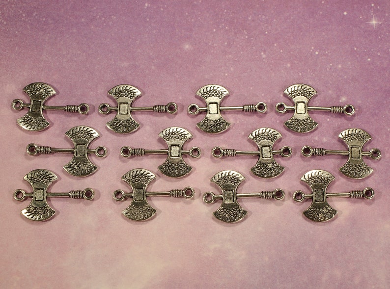 May include: Twelve silver axe-shaped charms with a decorative design. Each charm has two loops for attaching to jewelry or other crafts.
