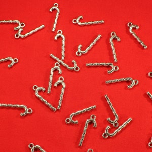 Op de afbeelding: Een verzameling zilverkleurige snoepstok-bedels, perfect om een feestelijke touch toe te voegen aan het maken van sieraden of knutselprojecten.