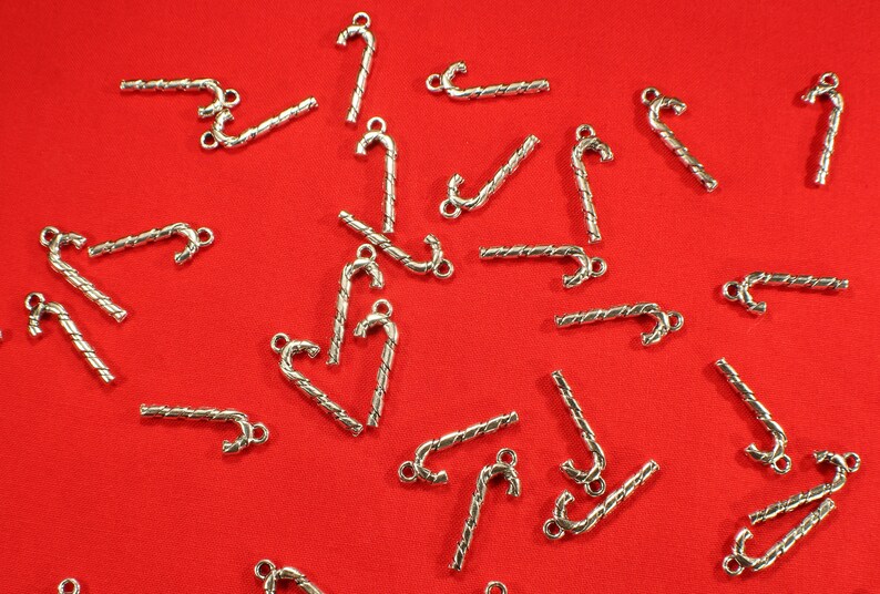 Op de afbeelding: Een verzameling zilverkleurige snoepstok-bedels, perfect om een feestelijke touch toe te voegen aan het maken van sieraden of knutselprojecten.