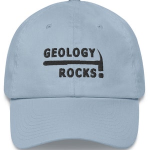 May include: A light blue baseball cap with black embroidery that reads "Geology Rocks!" with a pickaxe graphic above the text.