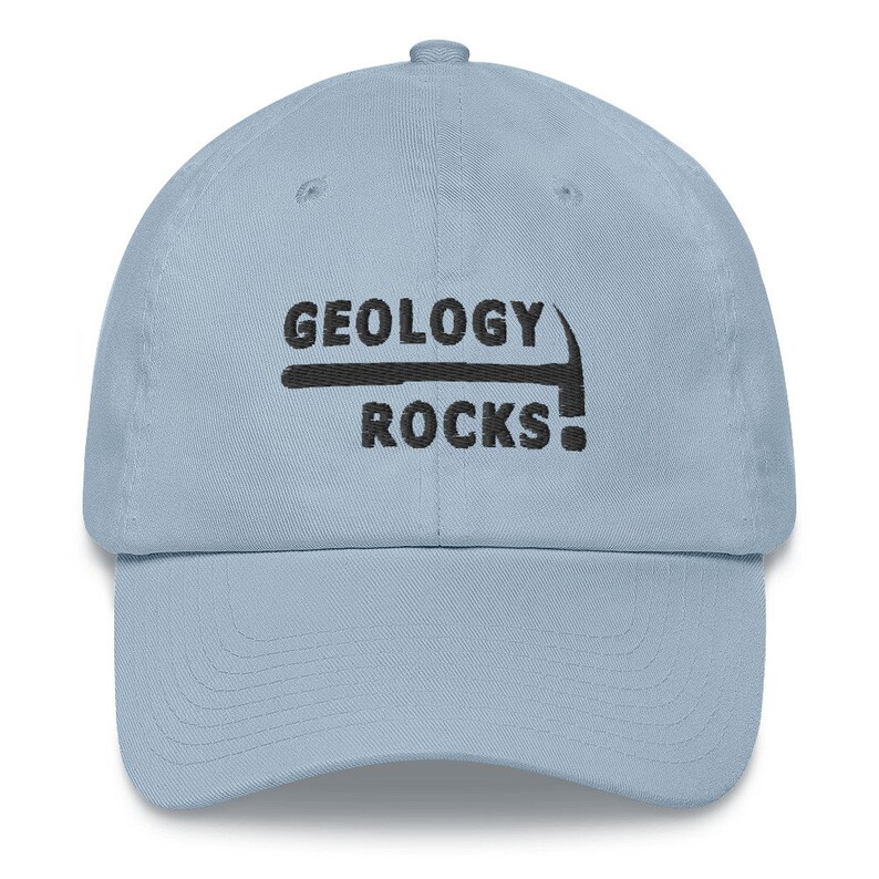 May include: A light blue baseball cap with black embroidery that reads "Geology Rocks!" with a pickaxe graphic above the text.