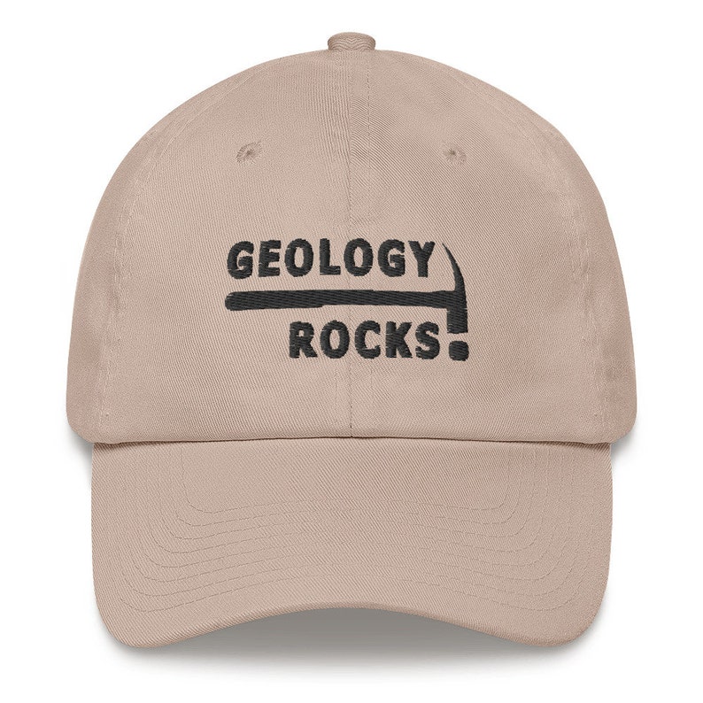 May include: A tan baseball cap with black embroidery that reads "Geology Rocks!" with a pickaxe graphic above the text.