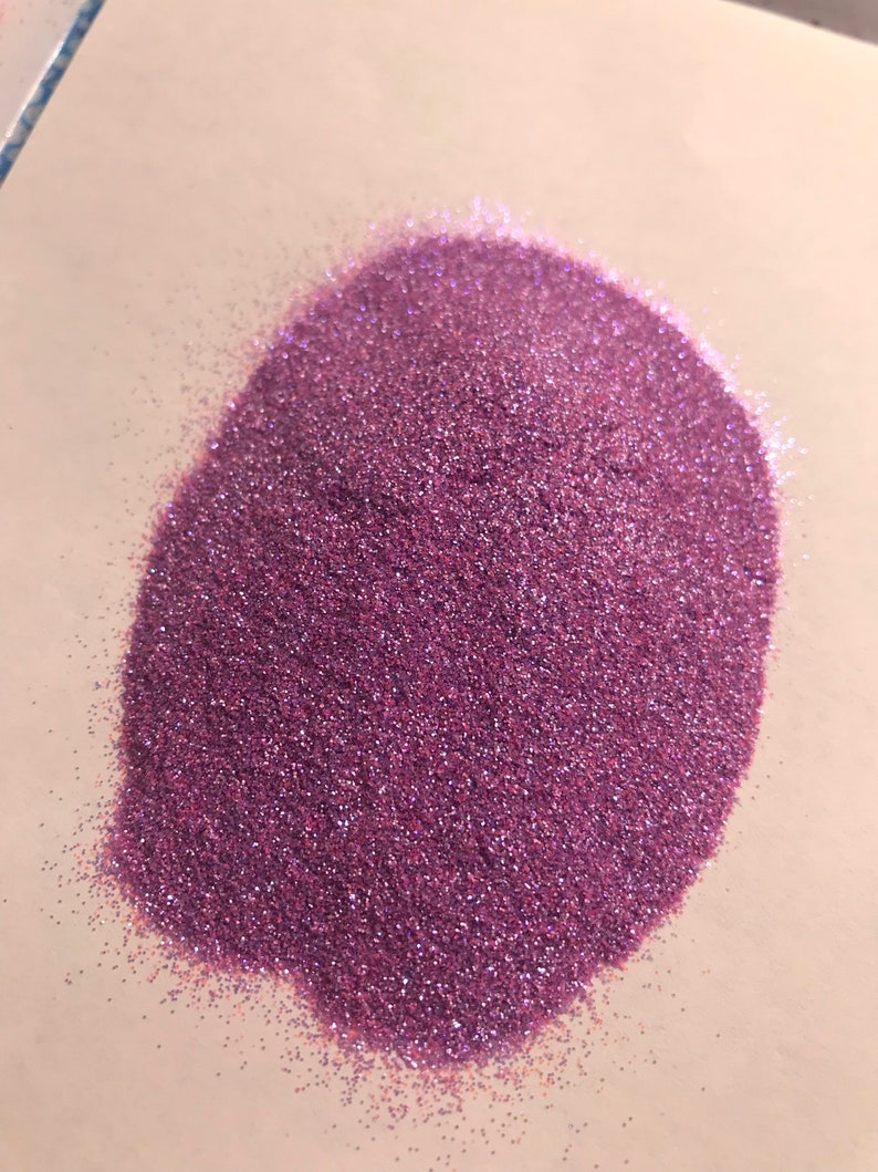 Op de afbeelding: Een hoop fijne, iriserende paarse glitter. De glitter is erg fijn en heeft een lichte glans.