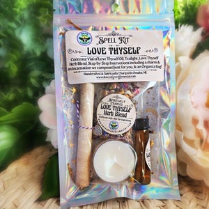May include: A spell kit for self-love with a tealight, a vial of oil, a charm, and a bag of herbs. The kit is packaged in a clear plastic bag with a holographic finish. The bag has a label that reads "Spell Kit Love Thyself" and includes instructions for use. The kit is handcrafted and spiritually charged.
