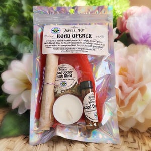 May include: A Spell Kit for Road Opener, containing a vial of oil, a tealight, a charm, an herb blend, and instructions. The kit is packaged in a clear plastic bag with a holographic finish.