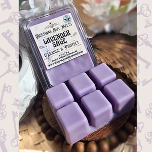 May include: Six lavender-colored wax melts in a clear plastic container. The container has a label that reads "Beeswax Soy Melts Lavender Sage Cleanse & Protect 2.75 oz / 78g Crafted & Blessed in Omaha, NE www.RavynGroveElemental.com".