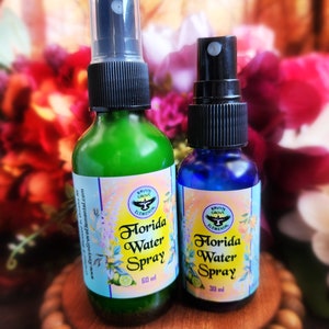 May include: Two glass spray bottles with black spray tops and blue and green labels. The labels read "Florida Water Spray" with a bird logo and the text "Ravyn Grove Elemental". The bottles are 60 ml and 30 ml.