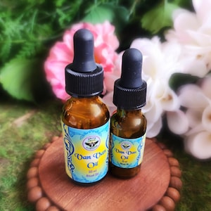 May include: Two amber glass bottles with dropper tops, labeled "Van Van Oil" in a yellow and blue design. The bottles are sitting on a wooden surface with a beaded edge.