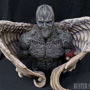 May include: A detailed bust sculpture of a demonic figure with large, feathered wings. The figure has a stone-like texture and green eyes. The sculpture is painted in shades of gray and red.