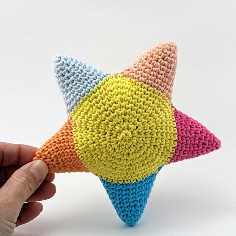 May include: A crocheted star-shaped plush toy with a yellow center and blue, pink, and orange sections.