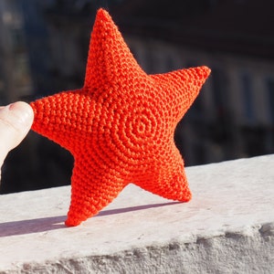 May include: A bright orange crocheted star with a spiral pattern in the center.