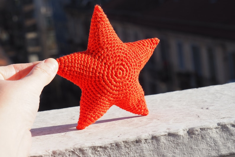 May include: A bright orange crocheted star with a spiral pattern in the center.