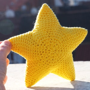May include: A yellow crocheted star-shaped pillow. The pillow is soft and fluffy, and it would be perfect for a child's room.