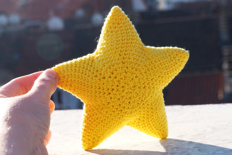 May include: A yellow crocheted star-shaped pillow. The pillow is soft and fluffy, and it would be perfect for a child's room.