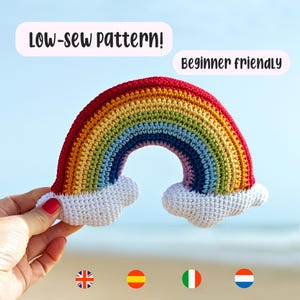 Peut inclure: Un arc-en-ciel crocheté composé de bandes de fil rouge, orange, jaune, vert, bleu et violet avec des nuages blancs à chaque extrémité. Le texte "LOW-SEW PATTERN!" et "Beginner friendly" figure au-dessus, avec quatre petits drapeaux circulaires.