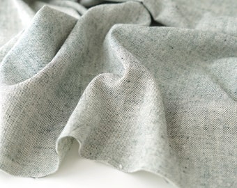 Könnte beinhalten: Nahaufnahme eines hellgrauen Stoffes mit einem dezenten, strukturierten Muster. Der Stoff ist gefaltet und drapiert und zeigt seine weiche und fließende Textur.
