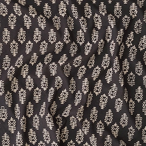 May include: Black fabric with a white geometric pattern of repeating stylised leaves and diamonds.