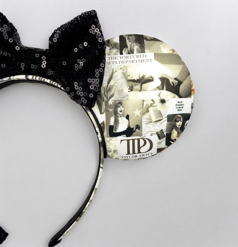 May include: Black and white patterned mouse ears with a black bow and a collage of images featuring Taylor Swift. The text "The Tortured Lets Department" and "But Daddy I Love Him" are visible on the ears. The text "T.S. Taylor Swift" is also visible.