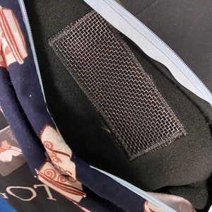 以下が含まれることがあります： 青いジッパーと内側にメッシュポケットが付いた黒いフード付きスウェットシャツ。フード付きスウェットシャツには、茶色と白のコーヒーカップの模様があります。