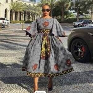 May include: A gray and brown patterned dress with a fitted bodice and a full skirt. The dress has a round neckline and 3/4 sleeves. The dress is cinched at the waist with a brown belt.