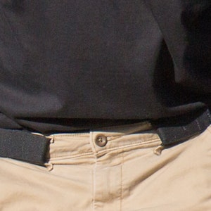 Close up of belt without buckle that attaches at side loops to pants. This is a stretch black belt that can be worn without the pinch other belts can cause.