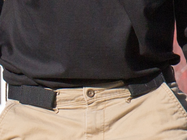 Close up of belt without buckle that attaches at side loops to pants. This is a stretch black belt that can be worn without the pinch other belts can cause.