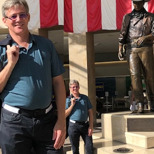 Man shown in white buckleless belt beside John Wayne statue in Orange County SNA airport.  Belt can be worn through airport security.