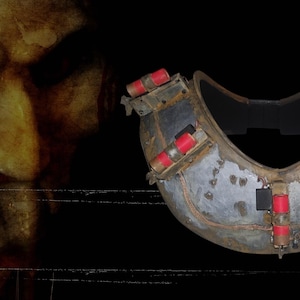May include: A metal head collar with red and white cylinders, a prop from the horror film franchise, Saw. The image also features a close-up of the Jigsaw killer's face with a spiral design on the cheek.