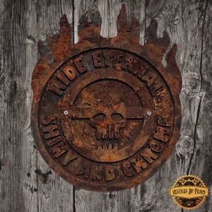 May include: A rusty metal sign with the words "RIDE ETERNAL SHINY AND CHROME" encircling a skull. The sign has a flame-like border and is mounted on a weathered wooden background. The sign also has the text "VESTIGES DU TEMPS 2018".