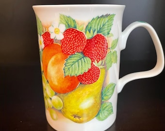 May include: White ceramic mug with a colorful fruit design. The design features a pear, peach, grapes, and strawberries.