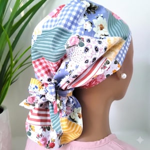 Op de afbeelding: Een operatiemuts met een patchworkontwerp van diverse bloemenpatronen, blauw-witte vichyruitjes en rood-witte strepen. Het stoffen hoofddeksel is voorzien van een striksluiting in de nek, wat zorgt voor een geplooid effect.