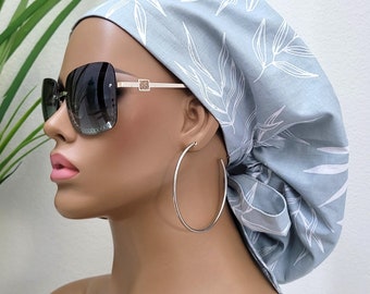 May include: A light blue surgical cap with a white leaf pattern. The cap is tied at the back of the head and has a gathered look.