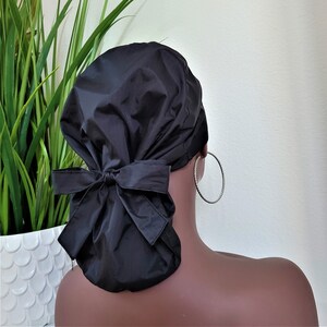 May include: Black satin sleep cap with a bow at the back. The cap is designed to protect hair while sleeping.