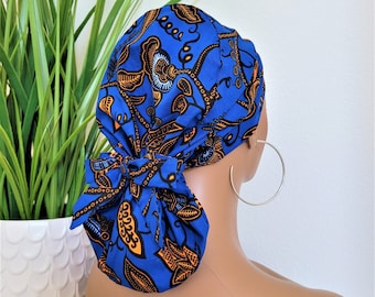 Puede incluir: Un gorro quirúrgico azul y naranja con estampado y un lazo en la parte posterior. El gorro está atado en un nudo en la parte posterior de la cabeza.