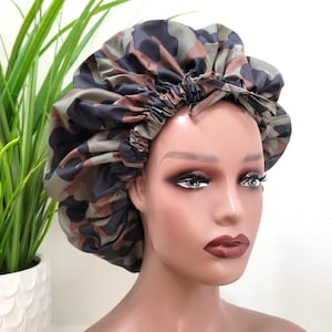 May include: A brown, green and black camouflage print satin sleep cap. The cap is gathered at the top and has a drawstring closure.