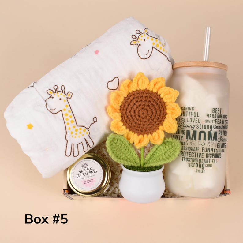 May include: A gift box with a white giraffe-patterned blanket, a crochet sunflower in a white pot, a glass jar with a straw, and a jar of succulents. The glass jar has the word "MOM" and other words printed on it. The box is labeled "Box #5".