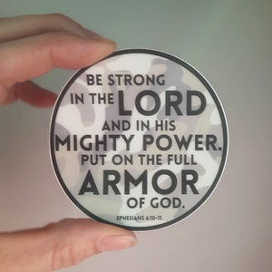 May include: A white and gray camouflage sticker with the text "Be strong in the Lord and in his mighty power. Put on the full armor of God. Ephesians 6:10-11"