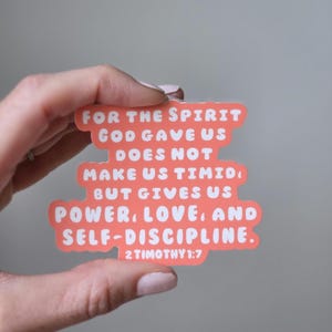 May include: A coral-colored sticker with white text. The sticker features the quote "FOR THE SPIRIT GOD GAVE US DOES NOT MAKE US TIMID, BUT GIVES US POWER, LOVE, AND SELF-DISCIPLINE. 2 TIMOTHY 1:7."