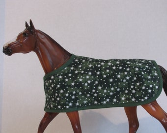 Op de afbeelding: Een bruin paardenbeeldje met een groen-witte sterrenpatroon deken. De deken heeft een donkergroene rand. Het paard staat op een witte achtergrond.