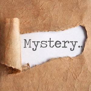 Puede incluir: La palabra "Misterio" se revela a través de un trozo de papel marrón rasgado.