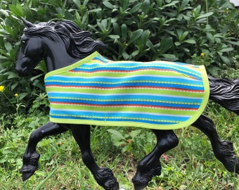 Op de afbeelding: Een zwart paardenmodel dat een groene, blauwe, witte en oranje gestreepte paardendeken draagt met een limoengroene rand.