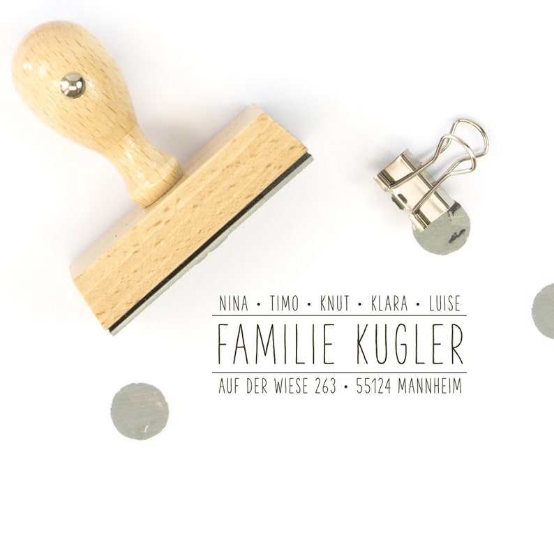 Pu&ograve; includere: Timbro in legno con manico e base rettangolare. Il timbro recita "Nina. Timo. Knut. Klara. Luise. Familie Kugler. Auf der Wiese 263. 55124 Mannheim."