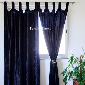 Puede incluir: Un par de cortinas de terciopelo azul oscuro con un amarre en el lado derecho. Las cortinas est&aacute;n colgadas de una barra de cortina plateada. El texto "Textile Tresor" es visible en el centro de la imagen.