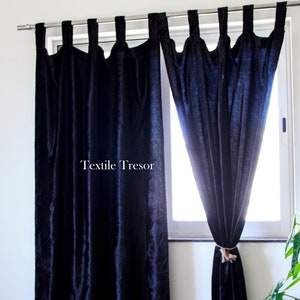 Puede incluir: Dos cortinas de terciopelo azul oscuro con lazos atados que cuelgan en una ventana. Las cortinas est&aacute;n reunidas en la parte superior y tienen un dise&ntilde;o simple y elegante. El texto "Textile Tresor" es visible en la cortina de la izquierda.