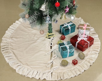 Puede incluir: Una falda de árbol de Navidad blanca con volantes, con un letrero dorado de "Feliz Navidad" y regalos envueltos en papel azul, rojo y plateado.