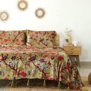 May include: A green velvet duvet cover with a floral and bird print. The duvet cover has a tassel trim and is shown on a bed with matching pillowcases.