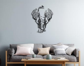 May include: Black metal wall art depicting an elephant with a tree-like design. The elephant's ears and head are formed by branches and leaves, with small birds perched on top. The artwork is mounted on a light blue wall above a gray sofa.